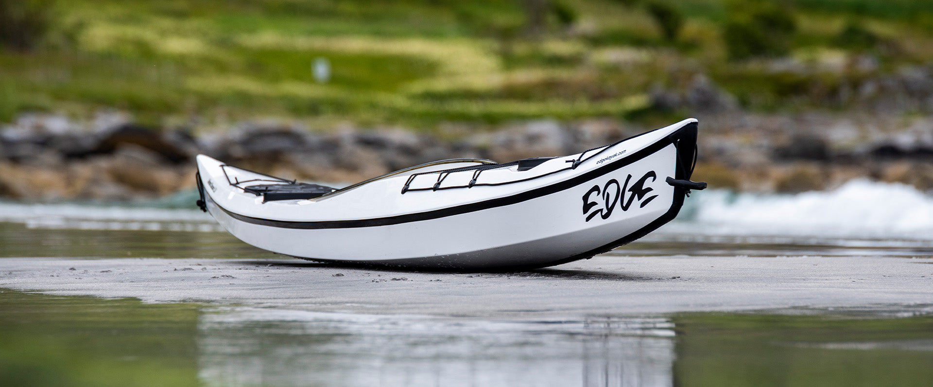 A white Edge kayak surfing a wave